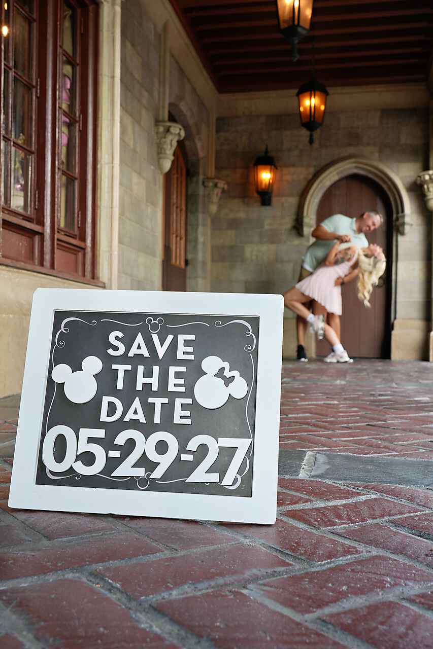 Save the Date chalkboard sign with couple in a dip kiss