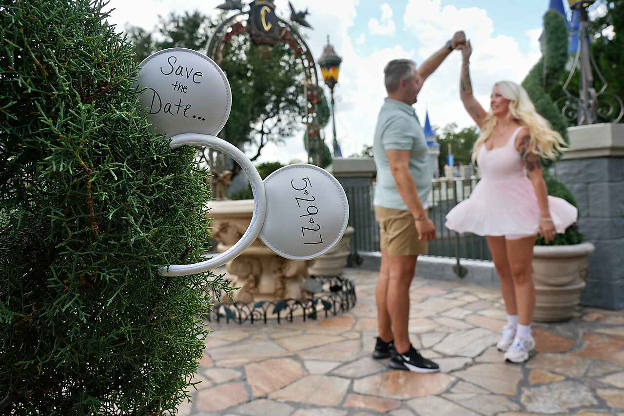 Save the Date Mickey ears tucked into a topiary with the couple dancing